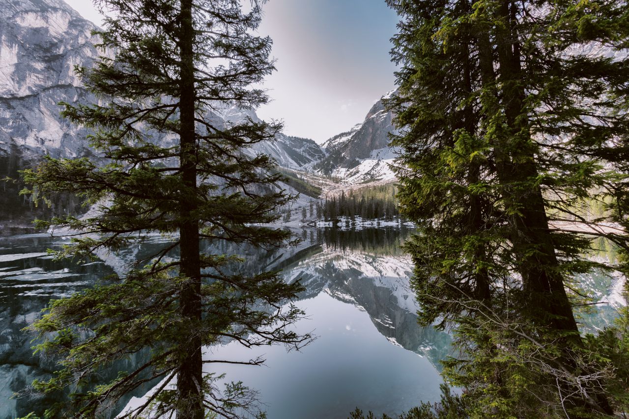 Breathtaking mountain lake view with snow-covered peaks and pine reflections.