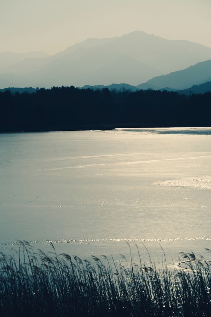 Serene twilight view of a tranquil lake with misty mountains in the background.